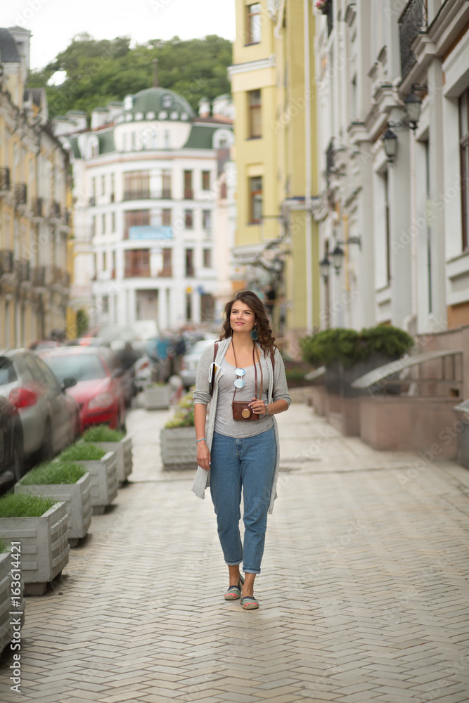 Young tourist woman walking in the street of the city. Snapshot of young beatiful travelgirl in full length.