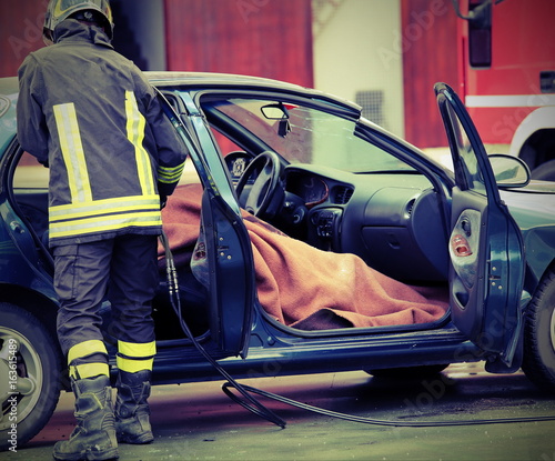 firefighter controls the person involved in a tragic car acciden photo
