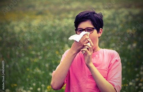 Young boy with pink t-shirt blowing his nose