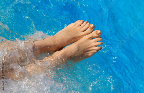 Bare feet of woman on the pool water