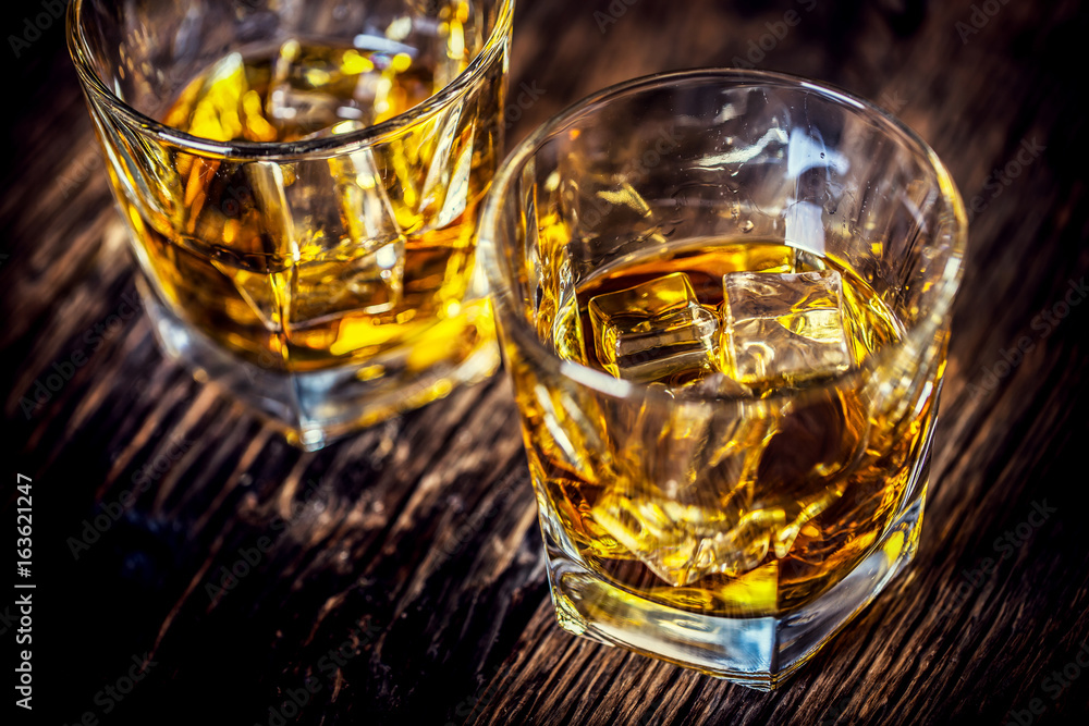 Whiskey drink. Whiskey drinks on rustic oak wood with ice cubes. Whiskey drink. Whiskey drinks on rustic oak wood with ice cubes.