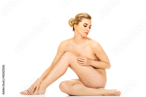 Young woman sitting on the floor and touching her legs