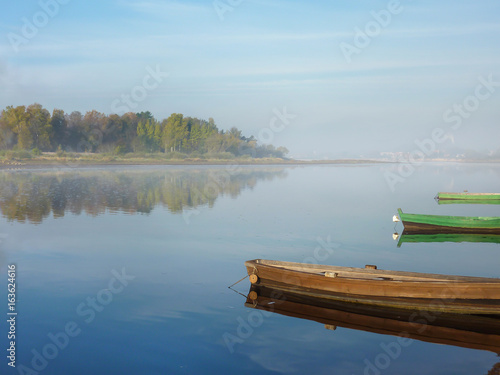 Beautiful waterscape in the early morning. Boats on the river at morning fog. Colorful scenery.