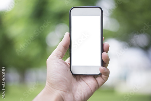 Close up man hand using smartphone in green park, Mockup of blank screen of smartphone