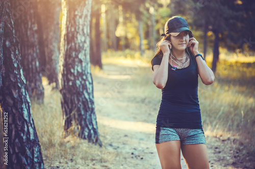 athletic woman listening music on a running in forest
