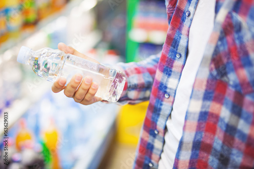 Man holding a bottle of water in grocery store