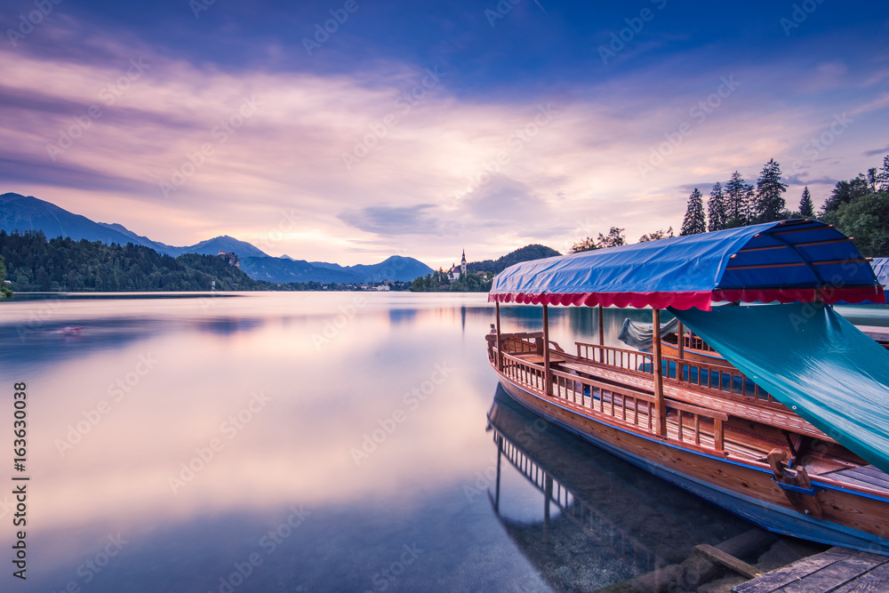 Wooden boat reflection in Bled lake at sunrise, Slovenia