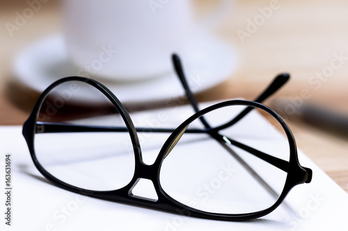 Glasses and cup of coffee on wooden table.