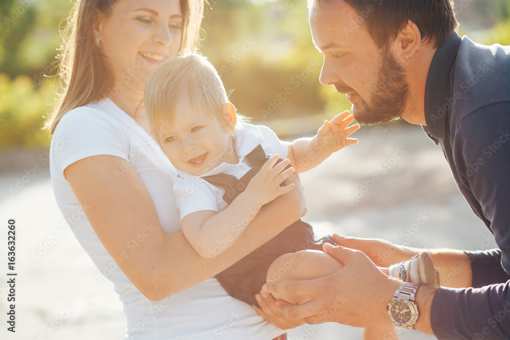 Fototapeta premium young mother and father playing with his daughter the evening in the Park