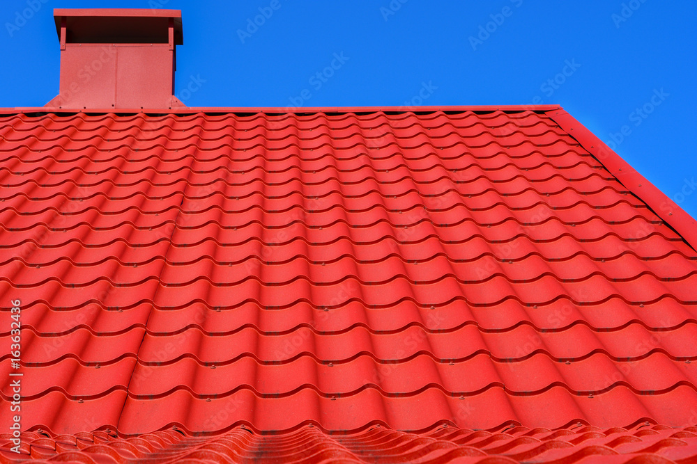 Fototapeta premium Red roof of a house against a blue sky.