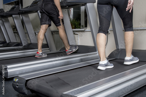 man and woman do fitness in the gym on the treadmill