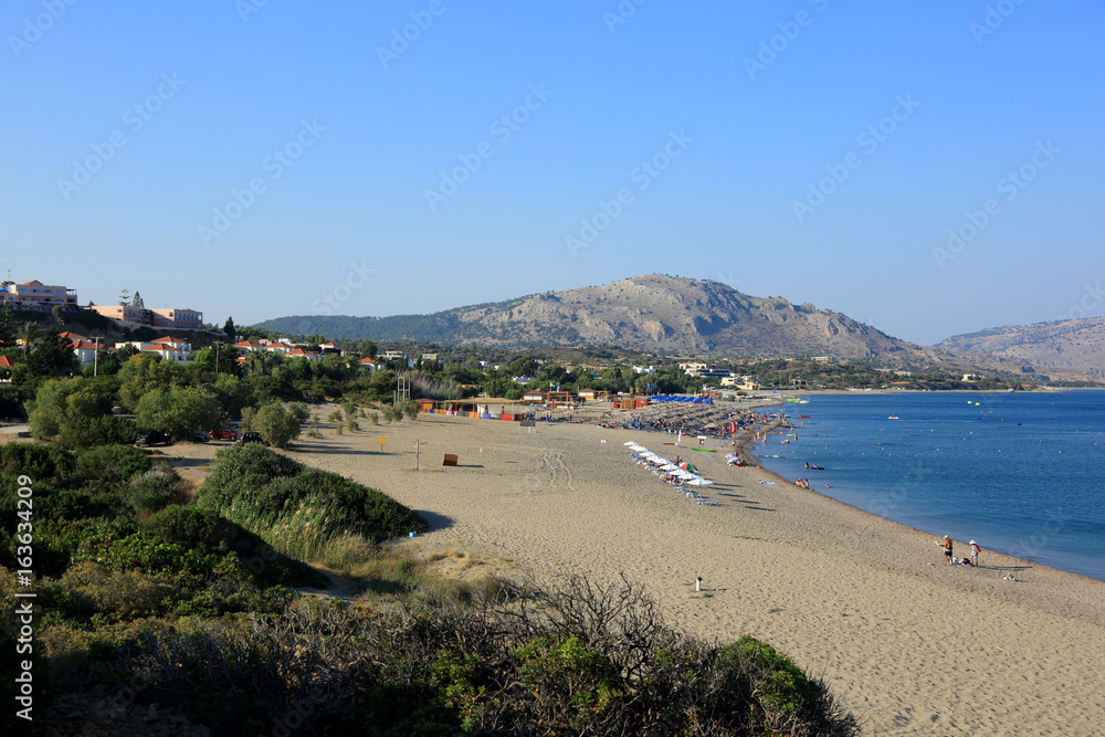 Piękna plaża na Rodos w Grecji, parasole i leżaki na plaży wzdłuż morza.