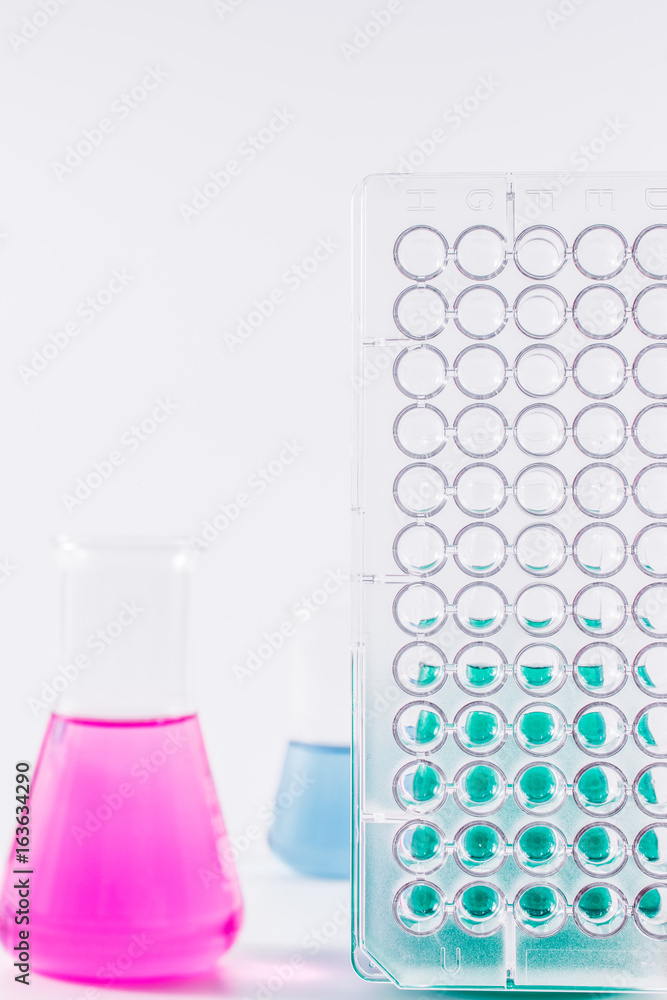  research, science and clinic background. 96 well micro plate and  laboratory beakers with colorful liquids and reagents.  