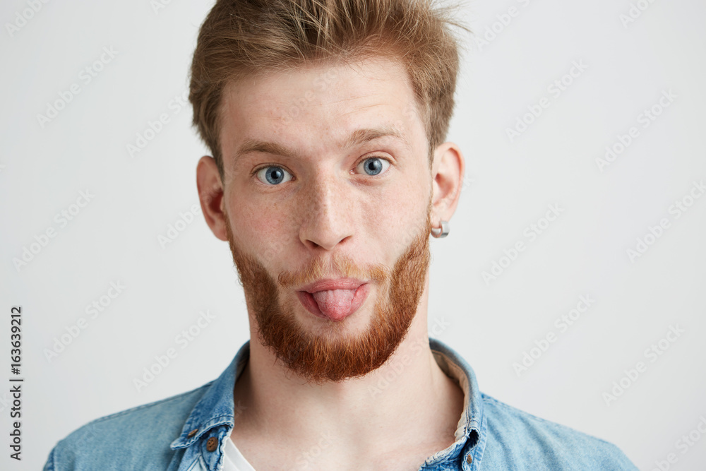 Portrait of young cheerful man looking at camera showing tongue over white background. Portrait of young cheerful man looking at camera showing tongue over white background.
