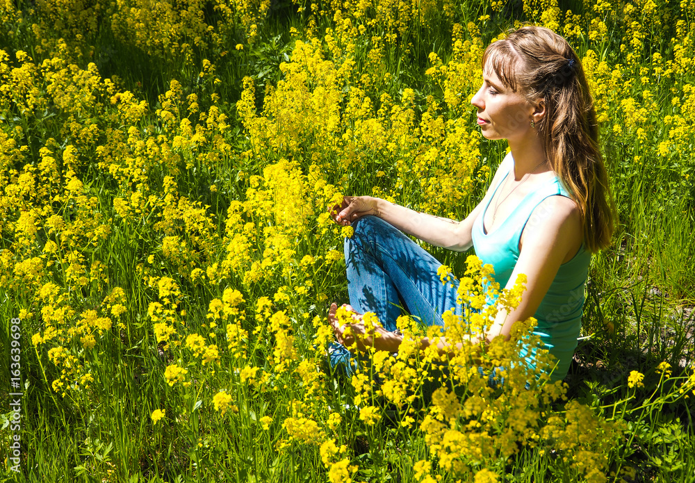 Fototapeta premium Lady is engaged in meditation in a city Park among yellow flowers. Beautiful woman doing yoga meditation in park. 