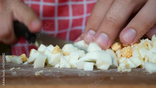 Cooking Salad in Home Kitchen. Boiled Egg Cutting on Chopping Board With Knife Close Up. Chefcook are Chopping Slices Eggs. Body Builder Cuts Egg Whites and Egg Yolk With Protein Before Training Gym photo