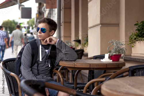 Young man resting sitting at a table on a city street