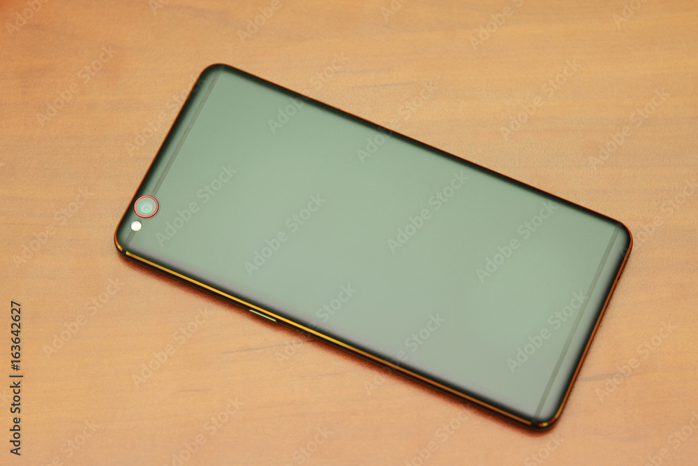 Black smartphone lying on a wooden table Black smartphone lying on a wooden table