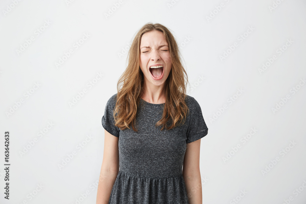 Portrait of emotive young beautiful girl shouting with closed eyes over white background. Portrait of emotive young beautiful girl shouting with closed eyes over white background.