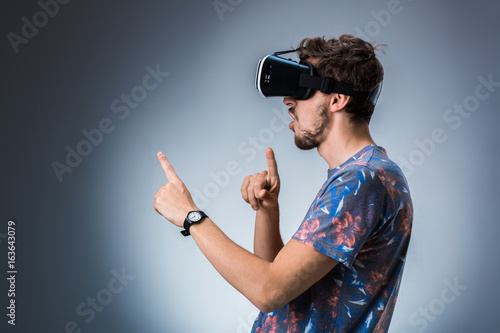 Side view of a young guy using a VR headset. Emotions