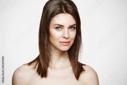 Nude young beautiful girl with natural make up smiling looking at camera over white background. Cosmetology and spa. Facial treatment. © Cookie Studio