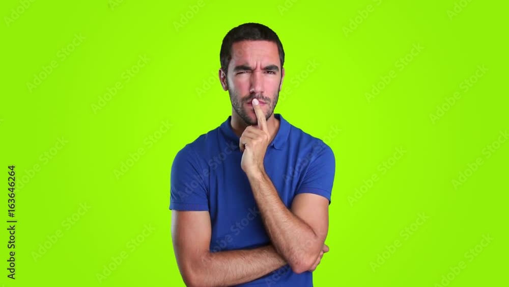 Suspicious young man on green background Suspicious young man on green background