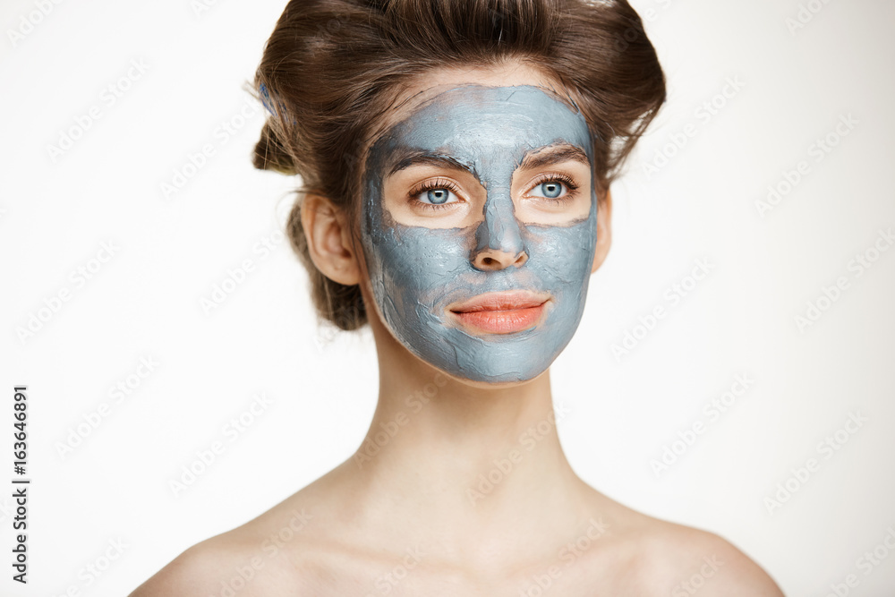 Beautiful tender naked girl in hair curlers and facial mask smiling over white background. Beauty health cosmetology and skincare. Beautiful tender naked girl in hair curlers and facial mask smiling over white background. Beauty health cosmetology and skincare.