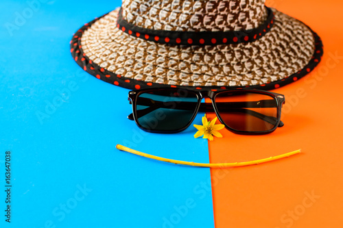 Sunglasses and hats on colorful blue and orange paper