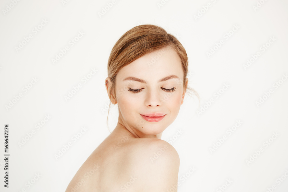Portrait of young naked beautiful girl with healthy clean skin smiling looking down over white background. Facial treatment. Portrait of young naked beautiful girl with healthy clean skin smiling looking down over white background. Facial treatment.