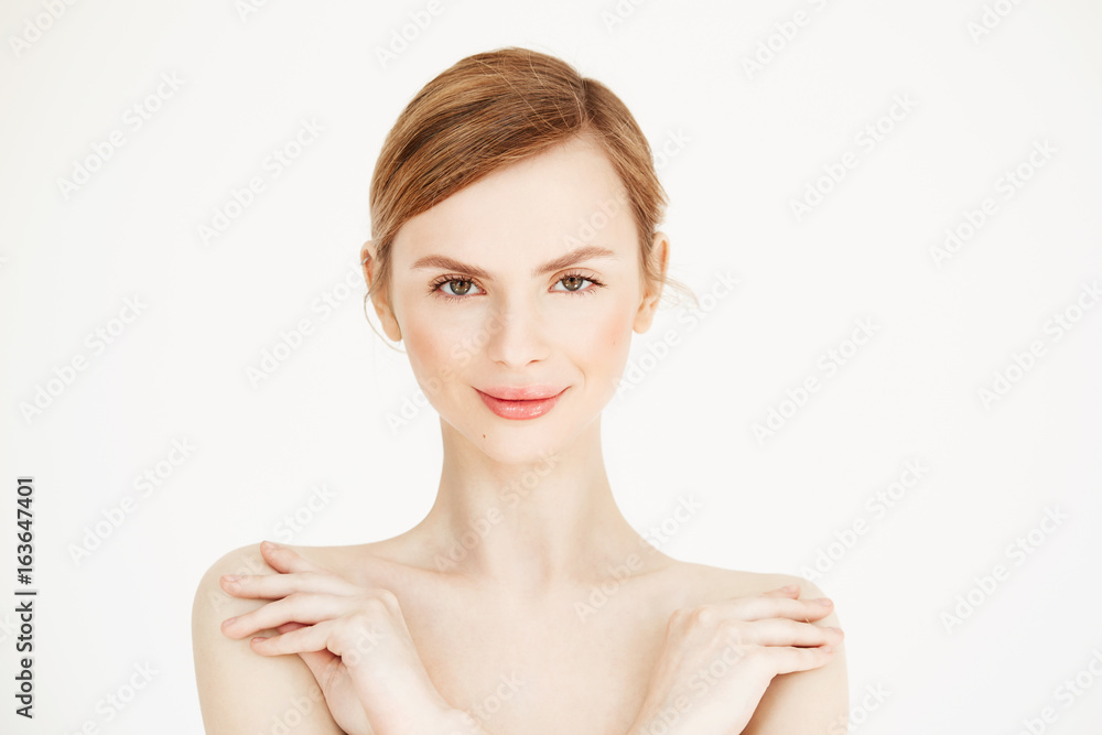 Portrait of young naked beautiful girl with healthy clean skin smiling looking at camera over white background. Cosmetology and beauty concept. Portrait of young naked beautiful girl with healthy clean skin smiling looking at camera over white background. Cosmetology and beauty concept.