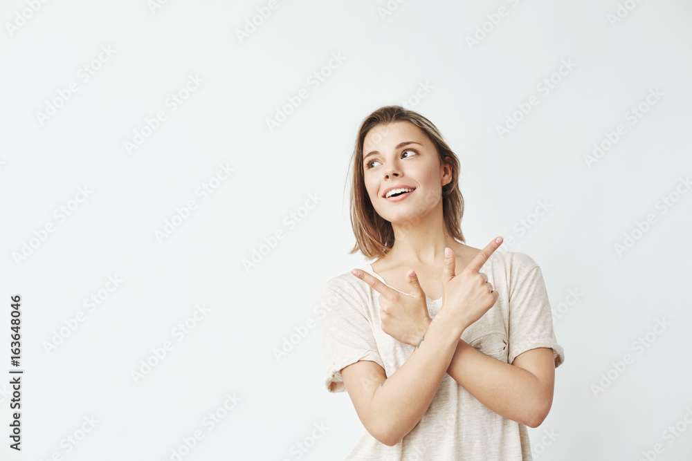 Happy sincere young girl pointing fingers up smiling over white background. Happy sincere young girl pointing fingers up smiling over white background.