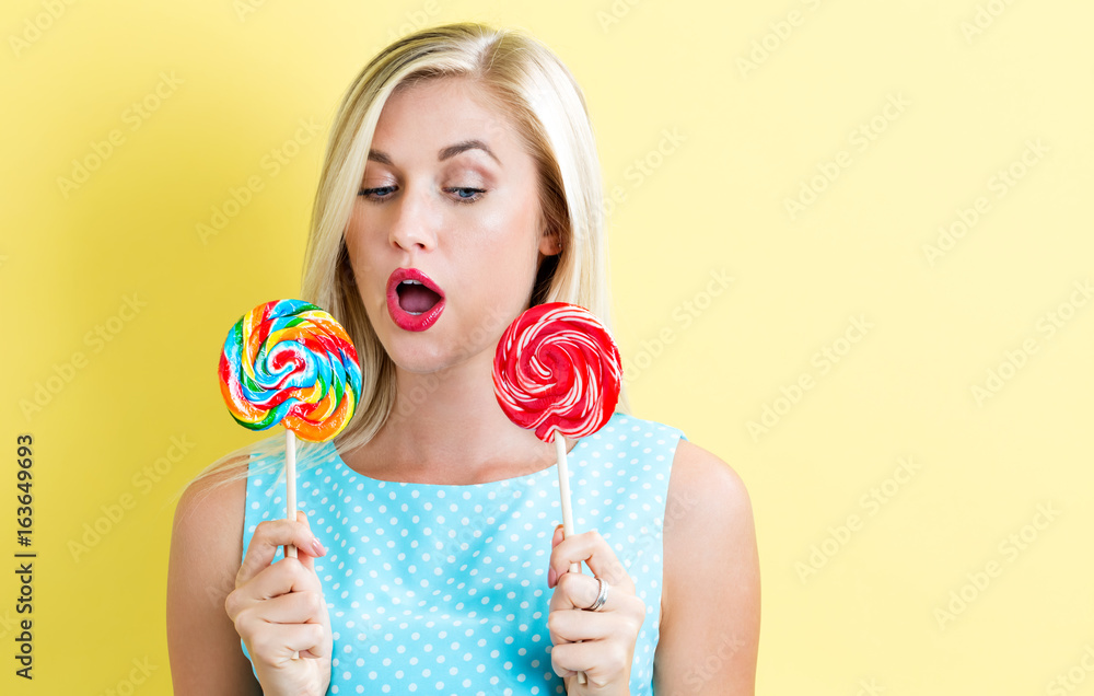 Young woman holding lollipops on a yellow background