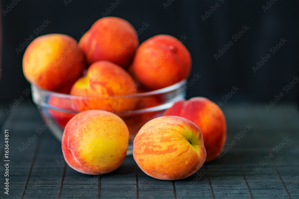 Ripe peaches in a transparent glass bowl on a black background. Summer fruits. Health Care Concept Ripe peaches in a transparent glass bowl on a black background. Summer fruits. Health Care Concept