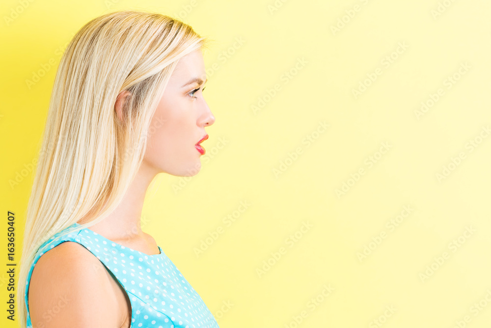 Obraz premium Profile of a young woman on a yellow background