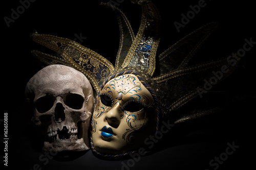 Human skull with venetian mask on a black background. Theater and drama concept