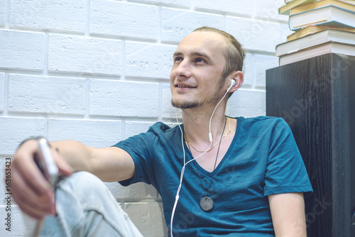 Young man in headphones listening to the audio book in home environment. Concept of technology and modern education