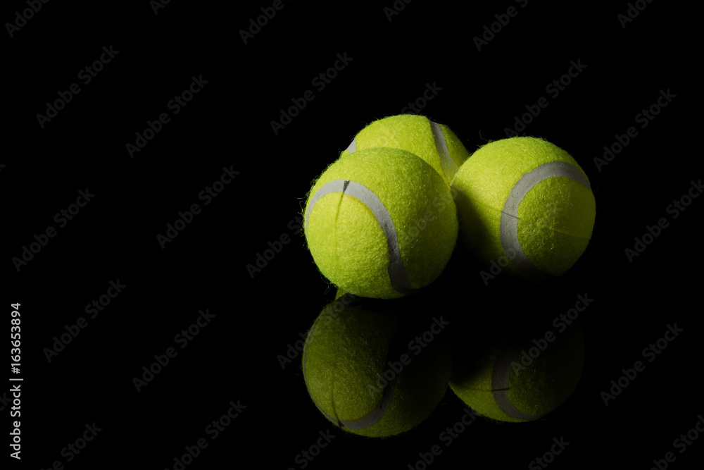 Three tennis balls isolated on a black background