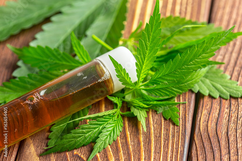 Cannabis leaves and oil on wooden background photo