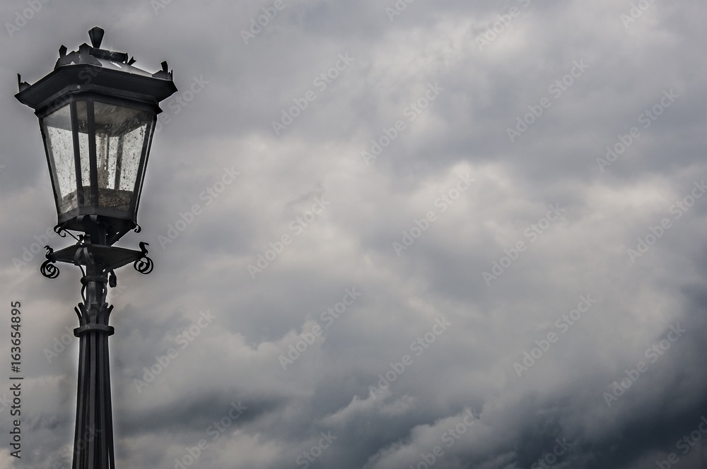 an antique lamp against storm clouds