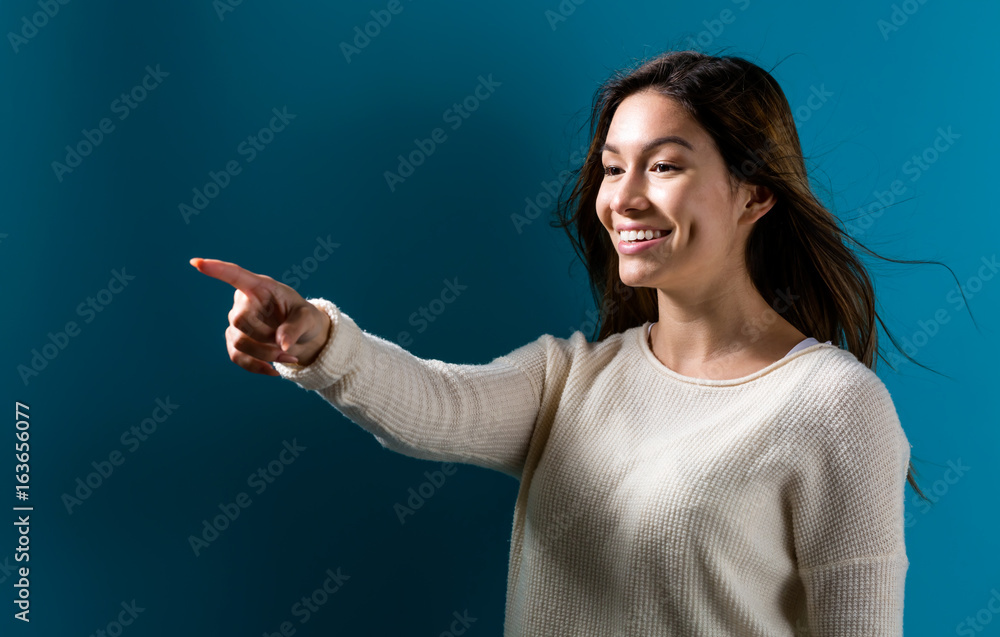 Young woman pointing something on a dark blue background Young woman pointing something on a dark blue background