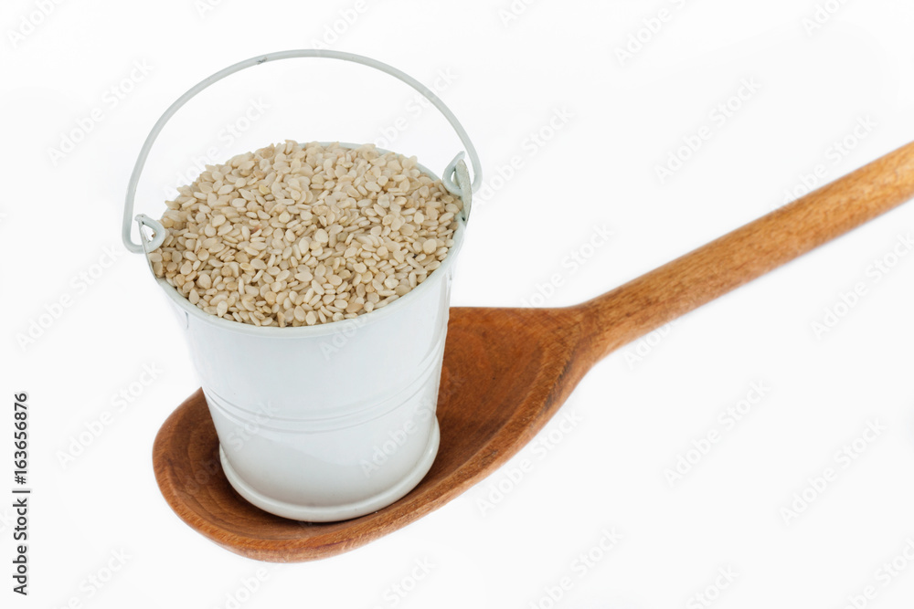 Full bucket of sesame grains stands in a wooden spoon. Full bucket of sesame grains stands in a wooden spoon.