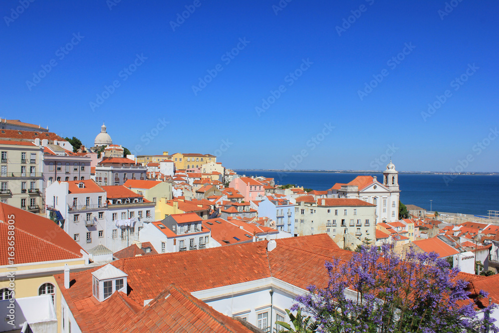 Beautiful panoramic wallpaper of Miradouro Portas do Sol viewpoint in Lisbon, Portugal. Rooftop view of Alfama old town historical district on summer time