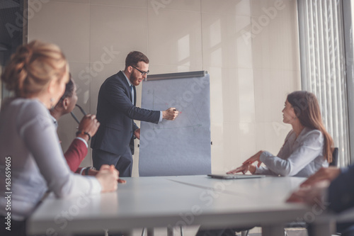 Confident handsome young businessman giving presentation using flipchart in office