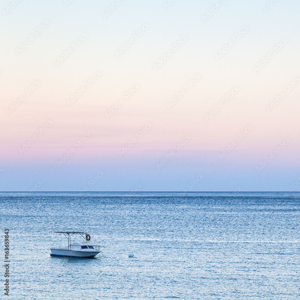 view of boat in sea in blue and pink twilight view of boat in sea in blue and pink twilight