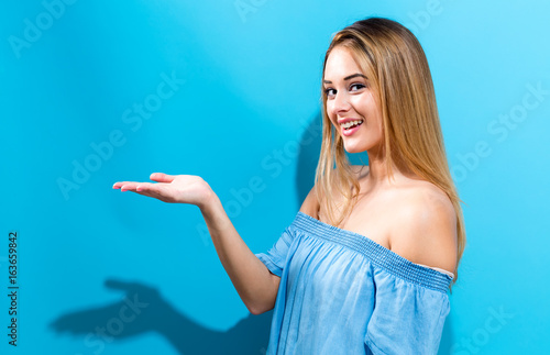 Young woman with a displaying hand gesture on a blue  background