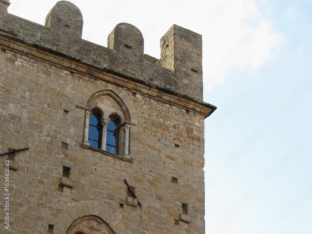 Detail of Palazzo dei Priori in Volterra village against the blue sky . Tuscany, Italy