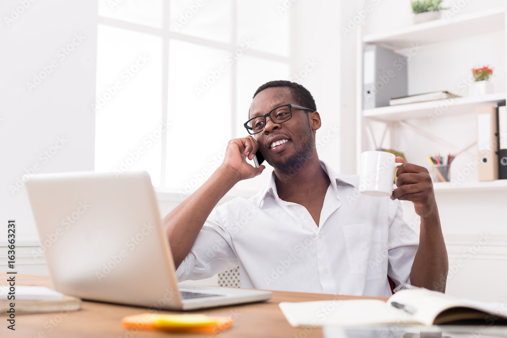 Relaxed young black businessman call mobile phone in modern white office Relaxed young black businessman call mobile phone in modern white office