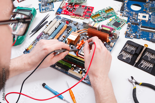 Engineer checking motherboard with multimeter