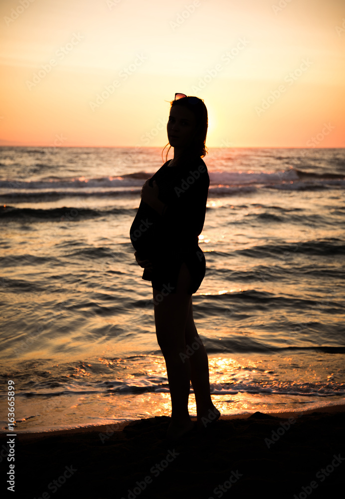 silhouette of a pregnant woman at sunset on the sea
