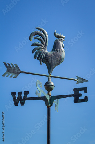 Weather vane showing direction of wind against clear blue sky, vertical photo